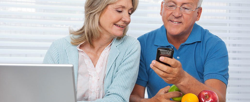 An Image of a Retired Couple Sitting At The Table Looking At The Phone Together Put On By Secure Money Advisors In Pittsburgh