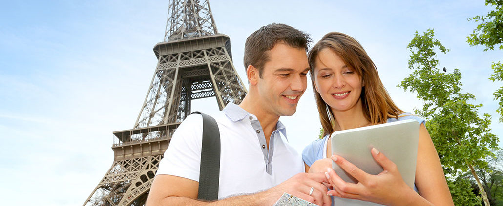 An Image Of A Young Couple Looking At A Tablet In Front Of The Eiffel Tower Put On By Secure Money Advisors In Pittsburgh