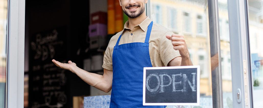 An Image Of A Man Holding An Open Sign For His Small Business Put On By Secure Money Advisors In Pittsburgh