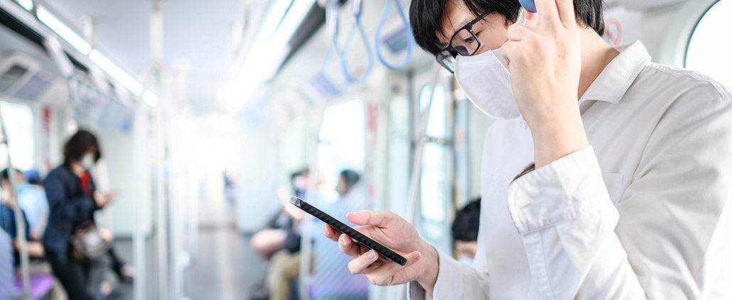 An Image Of A Man Wearing A Mask On A Train Looking At His Phone Put On By Secure Money Advisors In Pittsburgh